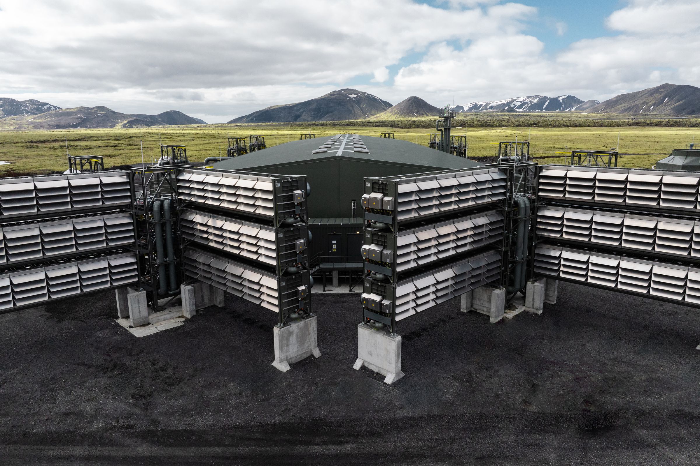 Large equipment that looks like stacked containers with slots running across it. A grassy valley and mountain range can be seen behind the equipment.