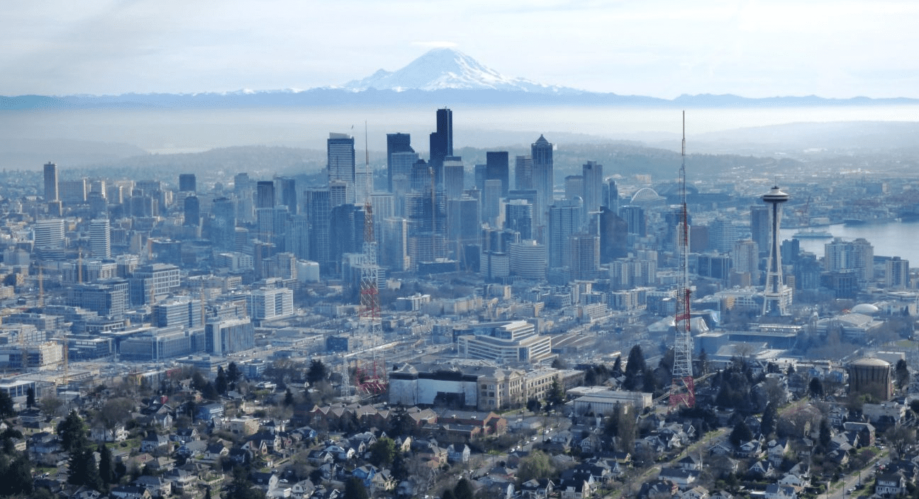 View of a cityscape with large buildings, radio towers, and a mountain in the background.