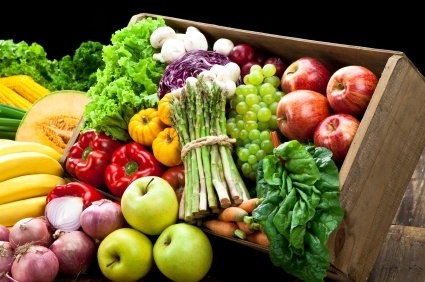 Basket of food including grapes apples asparagus onions lettuce carrots melon bananas corn