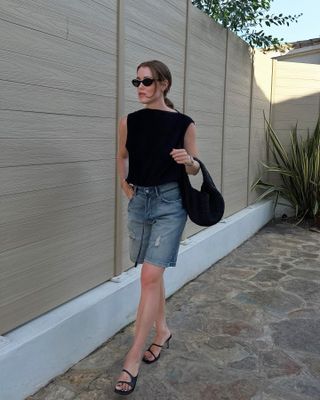 Stylish woman wearing denim shorts and a black top