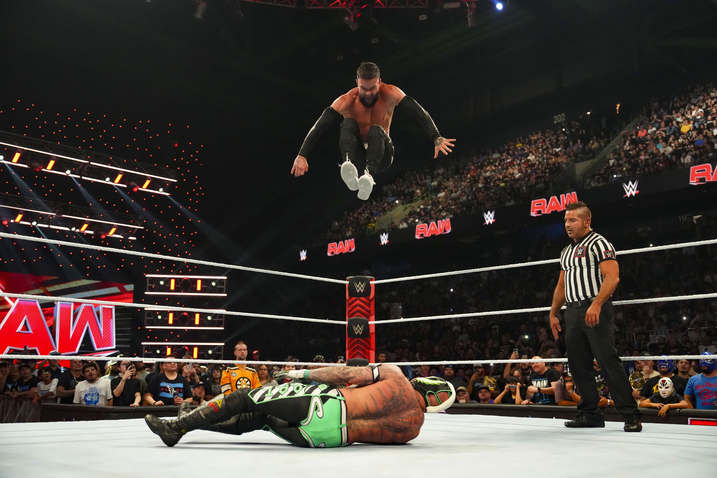 An image of a wrestler leaping from a height onto another wrestler in the ring. The referee watched from nearby. 