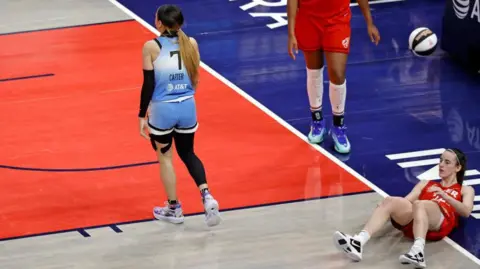 Getty Images Caitlin Clark lies on the ground last Saturday after she was shoulder checked by Chennedy Carter, a player for the Chicago Sky. 