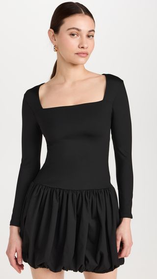 a model wears a black short long-sleeve dress with a bubble hem