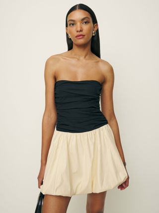 a model wears a black and white strapless dress with a bubble hem