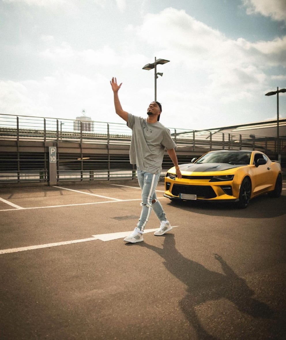 Benjamin Henrichs (27) mit seinem goldenen Auto Chevrolet Camaro