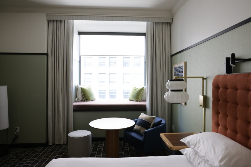 A partial view of the hotel's guest room showing a small seating area and bench seating in front of a window.