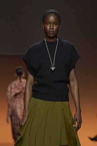 Bottega Veneta model wearing black top, green skirt, and long silver necklace