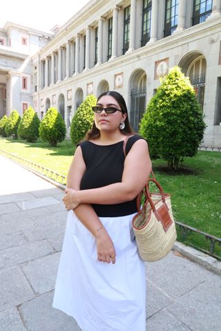 Woman wearing dress with black top and white full-length skirt.