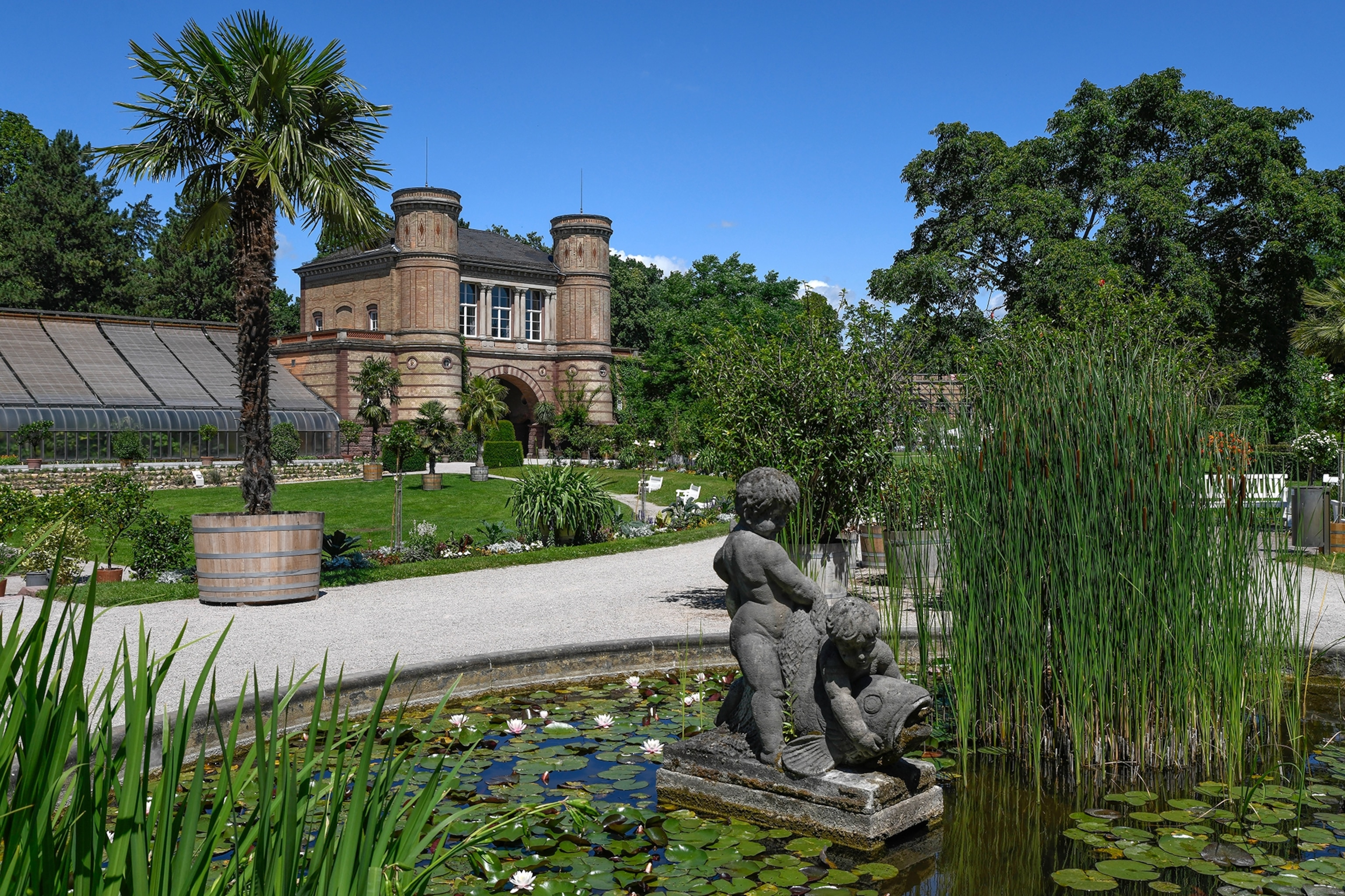 A fountain and stately building surrounded by greenery in the Karlsruhe Botanical Gardens in the state of Baden-Württemberg, Germany.