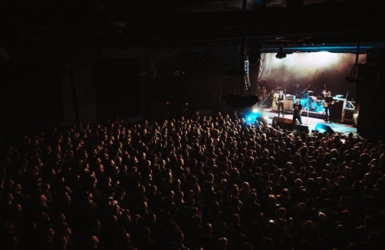 A band plays to a packed indoor audience of over a thousand at a theatre