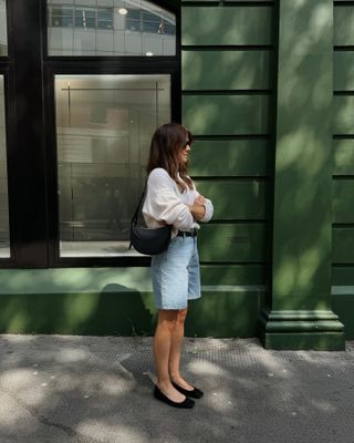 Influencer wears denim shorts and ballet flats.