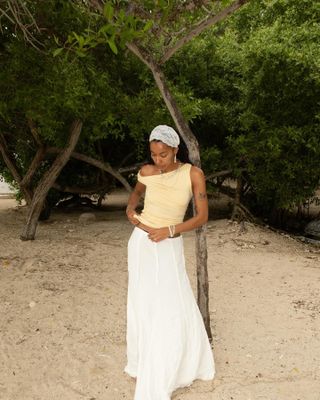 Woman wearing yellow top and white skirt. on the beach