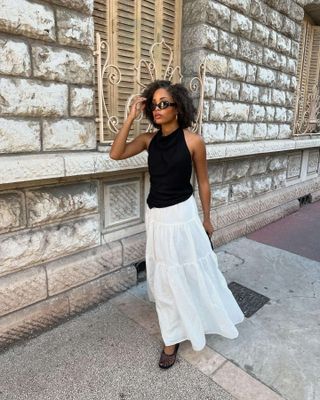 Woman in white maxi skirt and black top.