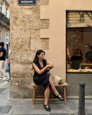 Influencer wears a black midi skirt and mary janes.