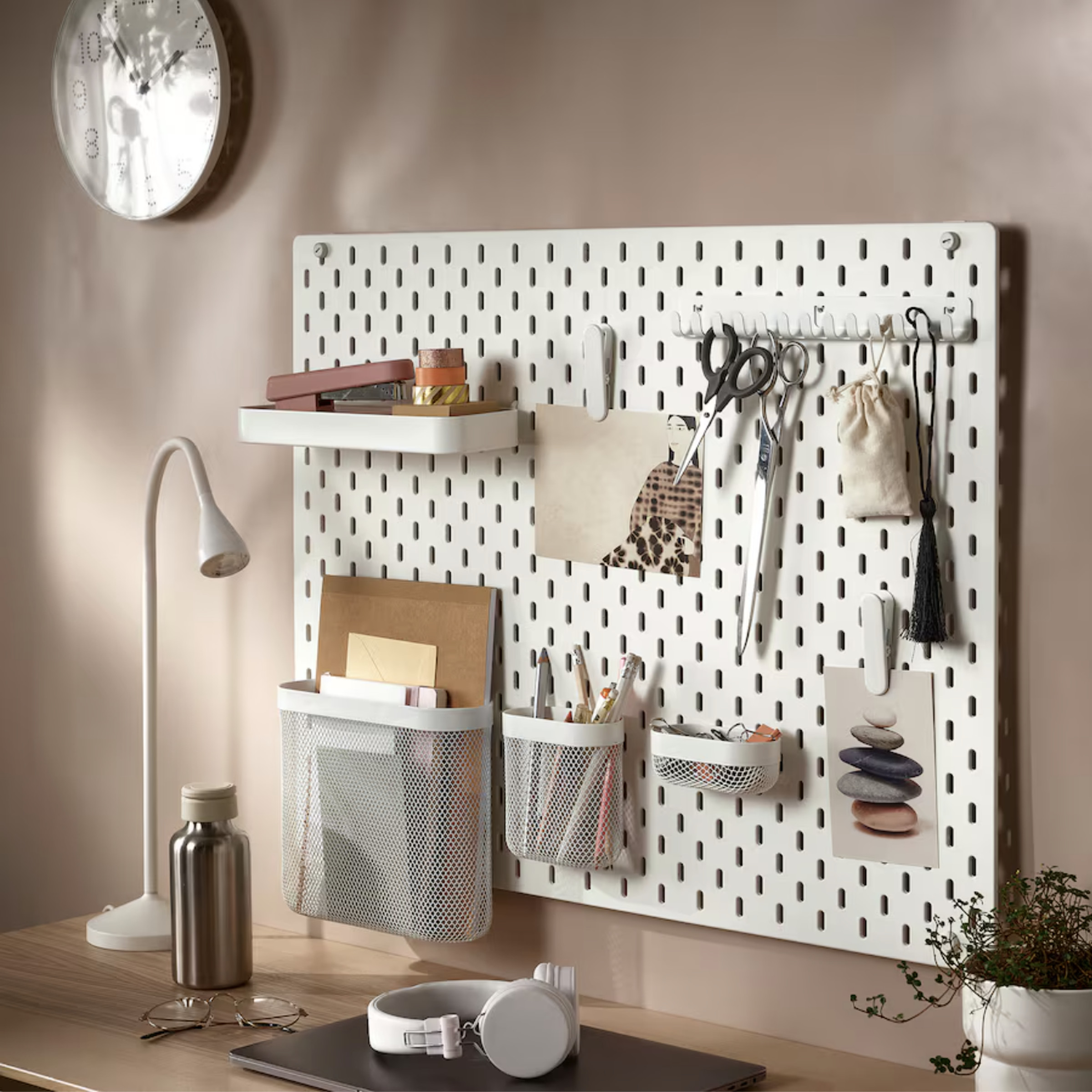 White pegboard with a variety of tools hanging from it.