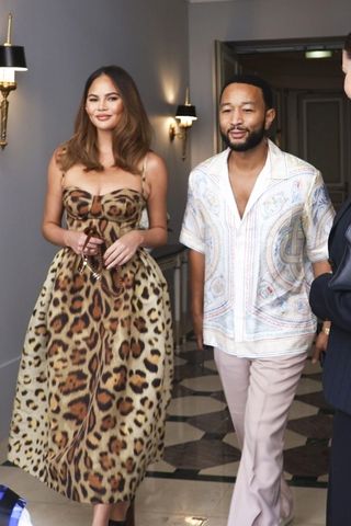 Chrissy Teigen wearing a leopard print dress with John Legend