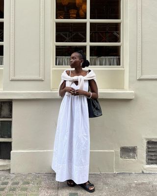 @daniellejinadu wearing a white dress with black sandals