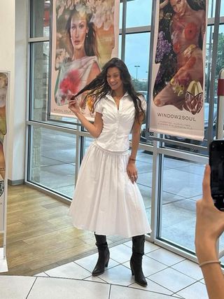 Bella Hadid wearing a white maxi skirt and black boots at an Orebella launch event at Ulta