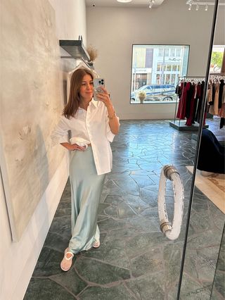 Judith Jones wearing a white button-down shirt and turquoise maxi slip skirt from Reformation x Laura Harrier in the brand's Beverly Hills store.