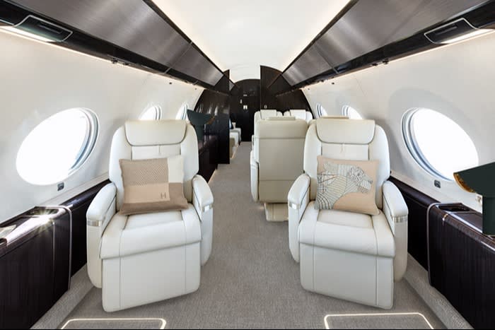 A pair of luxurious reclinable white leather seats in the cabin of a small jet