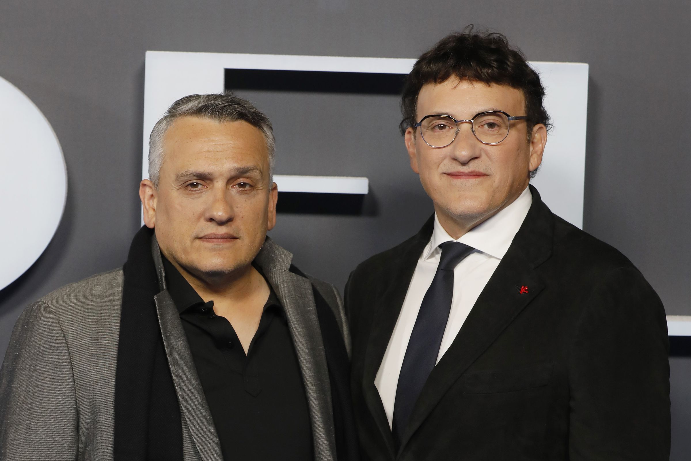 Two men in evening wear standing side-by-side on a red carpet.