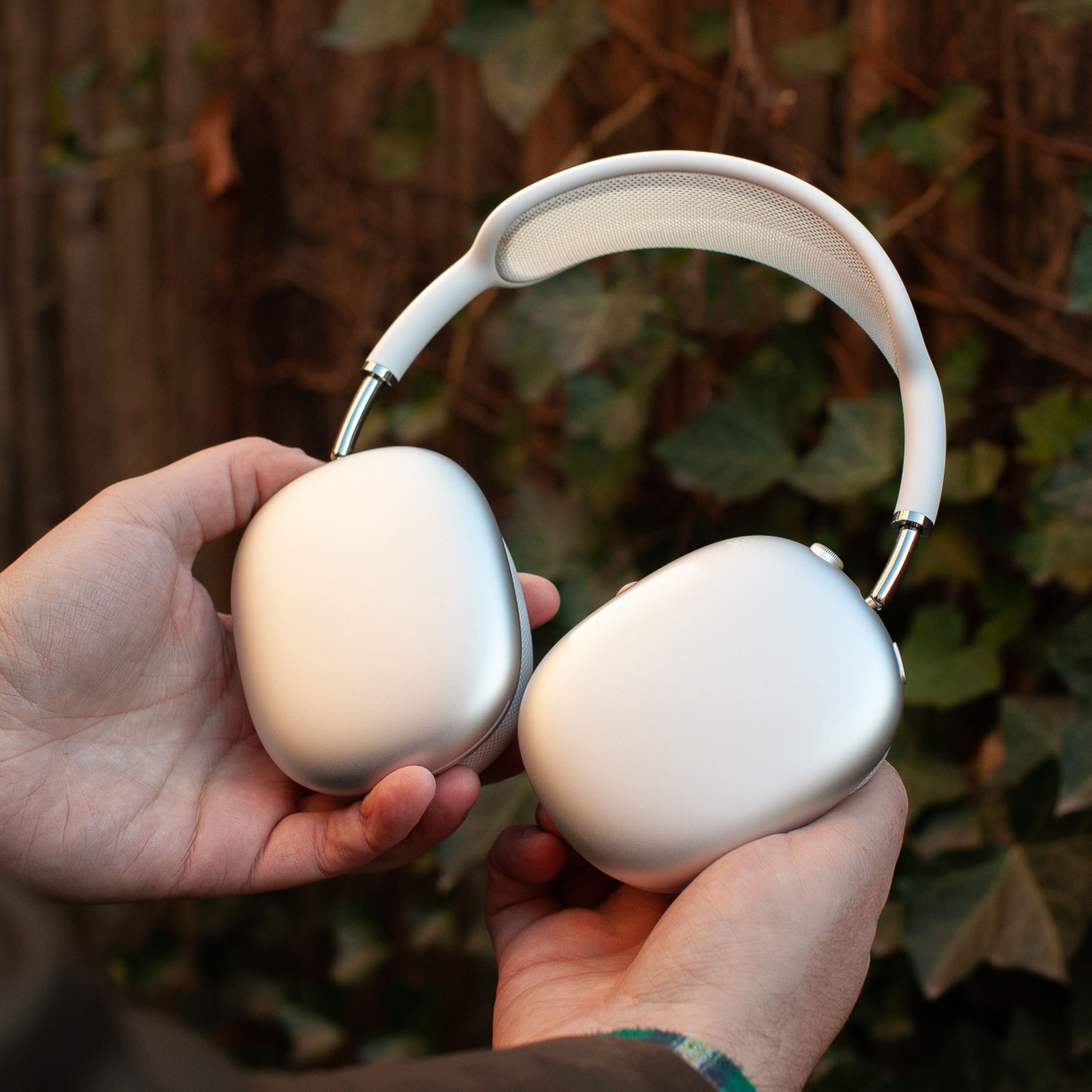 A hand holding the silver Apple AirPods Max.