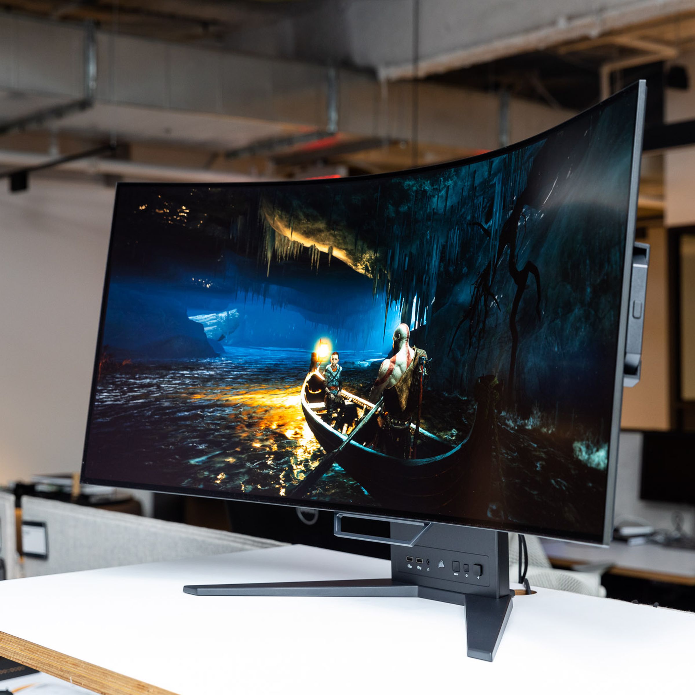 A side view of the Corsair Xeneon Flex OLED gaming monitor, showing a still photo of 2018 God of War on PC.