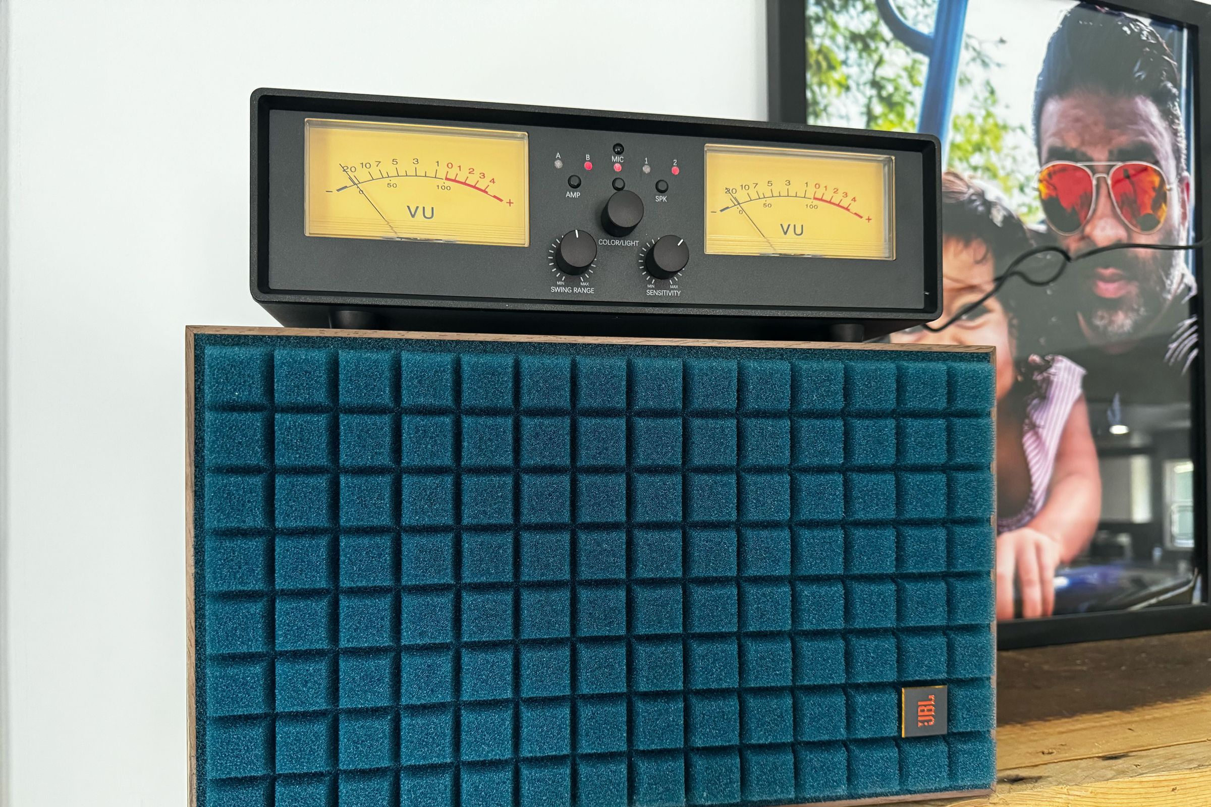 An image of an inexpensive VU meter atop a turquoise blue JBL speaker.