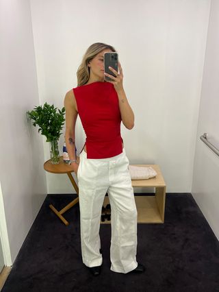 Eliza Huber wearing a red bateau-neck sleeveless top with white linen pants at the COS store.