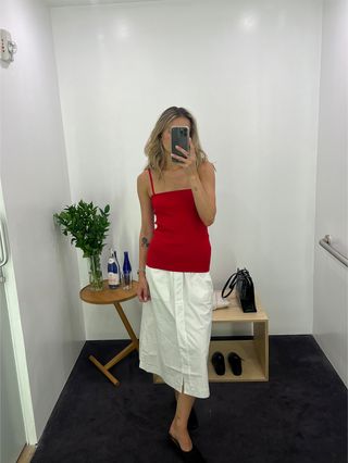 Eliza Huber wearing a red spaghetti strap top with a white poplin skirt at the COS store.