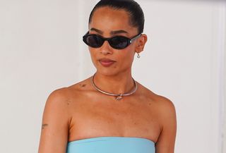 Zoe Kravitz seen attending the Lenny Kravitz Hollywood Walk of Fame Star Ceremony on March 12, 2024 in Los Angeles, California wearing a turquoise strapless top, silver collar necklace, and black sunglasses.