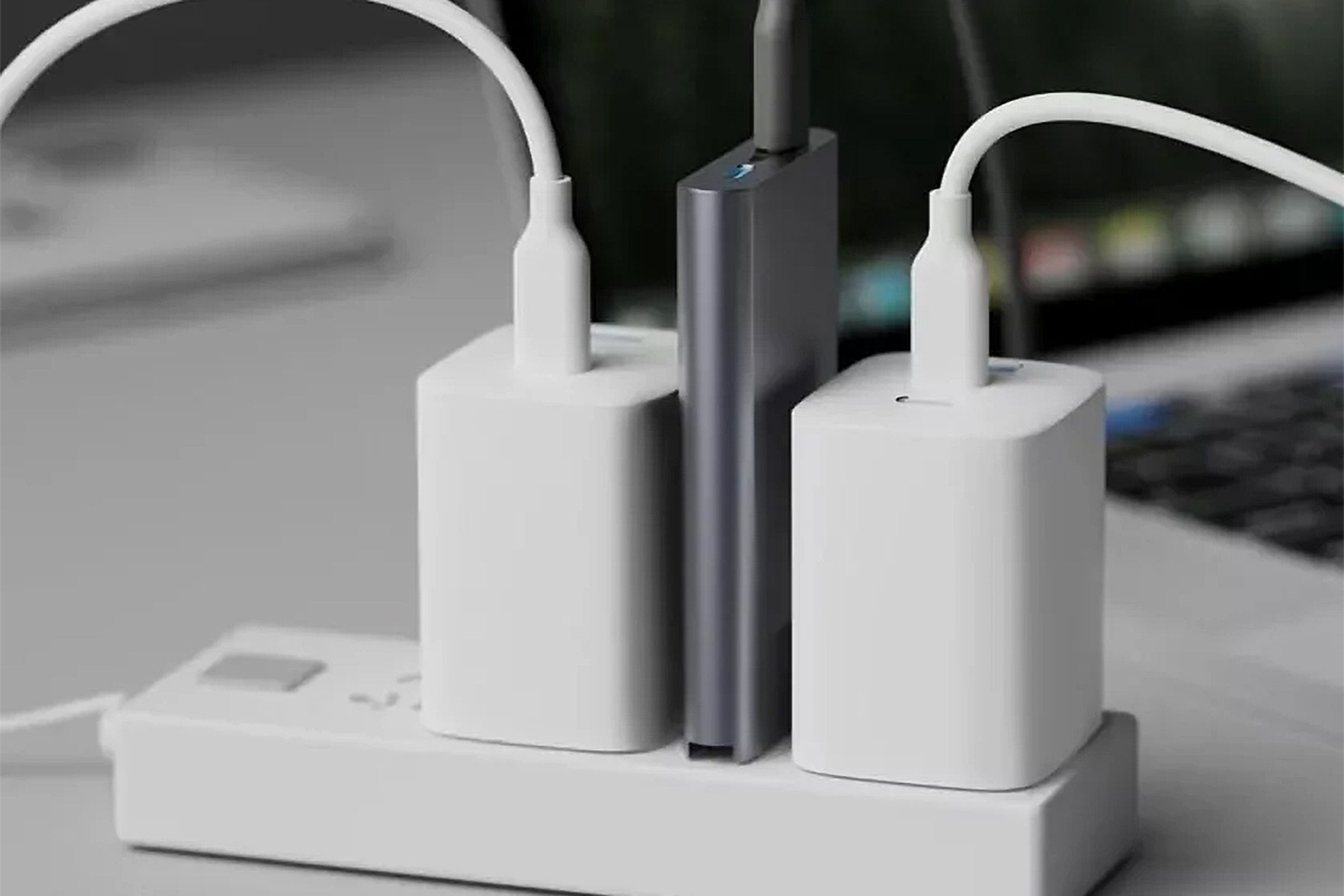 Anker’s upcoming 65W Prime charger plugged into a small power strip between two larger power adapters.