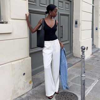 Woman wearing black tank top and white pants.