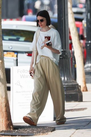 Lily Collins wore grey trousers and Adidas trainers.