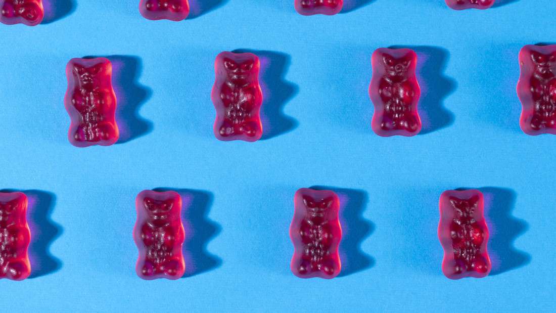 Rote Gummibärchen in Reihen, auf blauem Hintergrund 