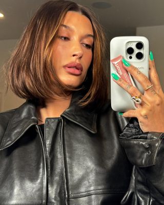 Hailey Bieber with brown lip liner and Rhode phone case with lip peptide in toast