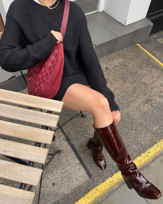 Autumn Boot Trends 2024: Influencer wears patent burgundy boots with a black miniskirt