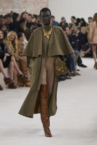 Woman on runway in khaki trench coat.