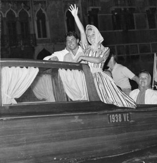 Brigitte Bardot waves at the camera from a boat at the Venice Film Festival