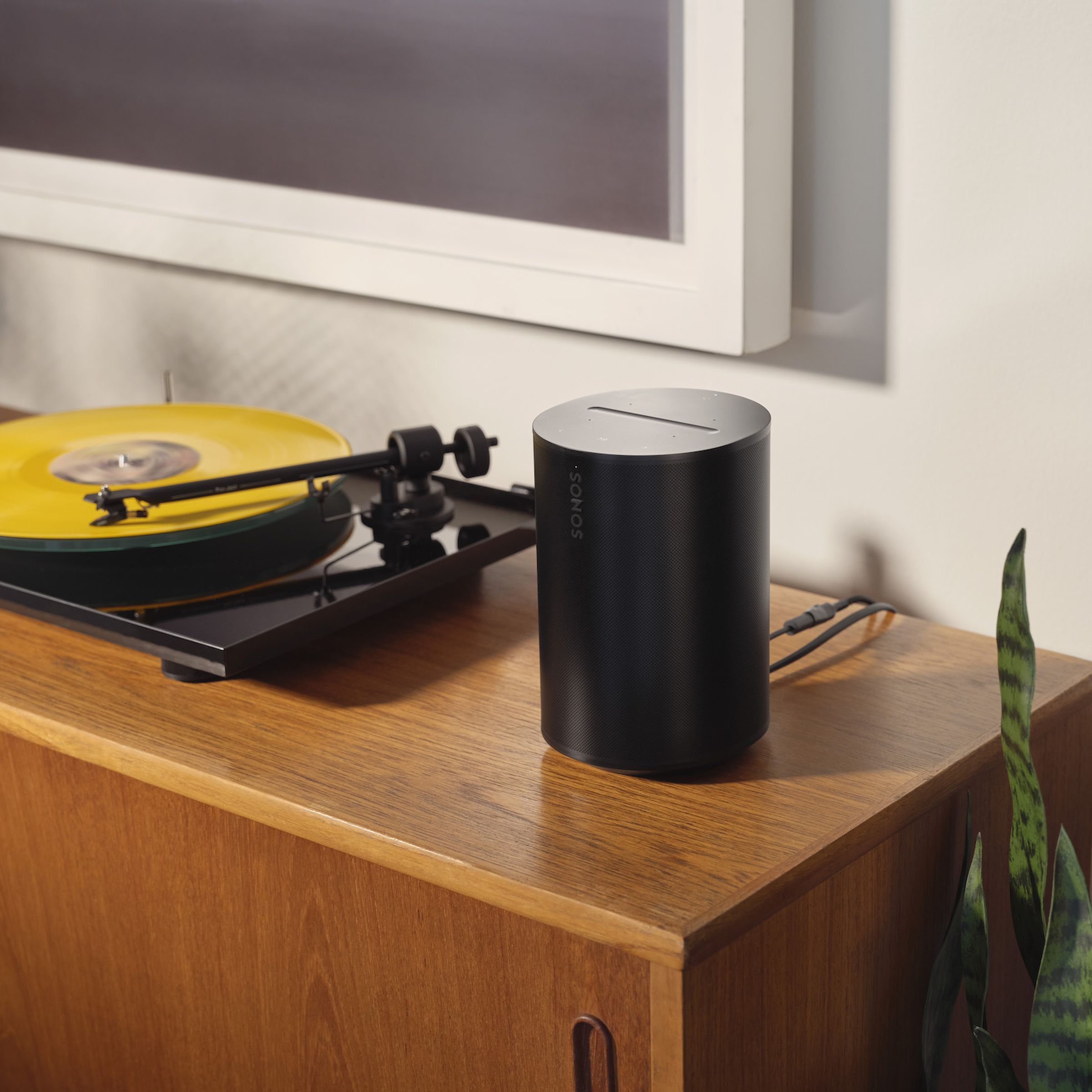 A photo of a Sonos Era 100 beside a turntable.