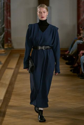 The navy color trend shown on Lovechild1979's runway worn by a model wearing a black turtleneck layered under a navy dress styled with a black belt and black shoes