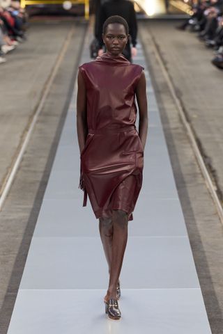 Model wearing burgundy leather dress on runway at Tod's Fall/Winter 2024.