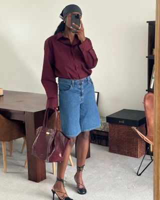 Woman wearing a burgundy button-down and holding a burgundy handbag.