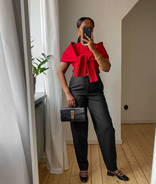 @femmeblk wearing a red top with black trousers