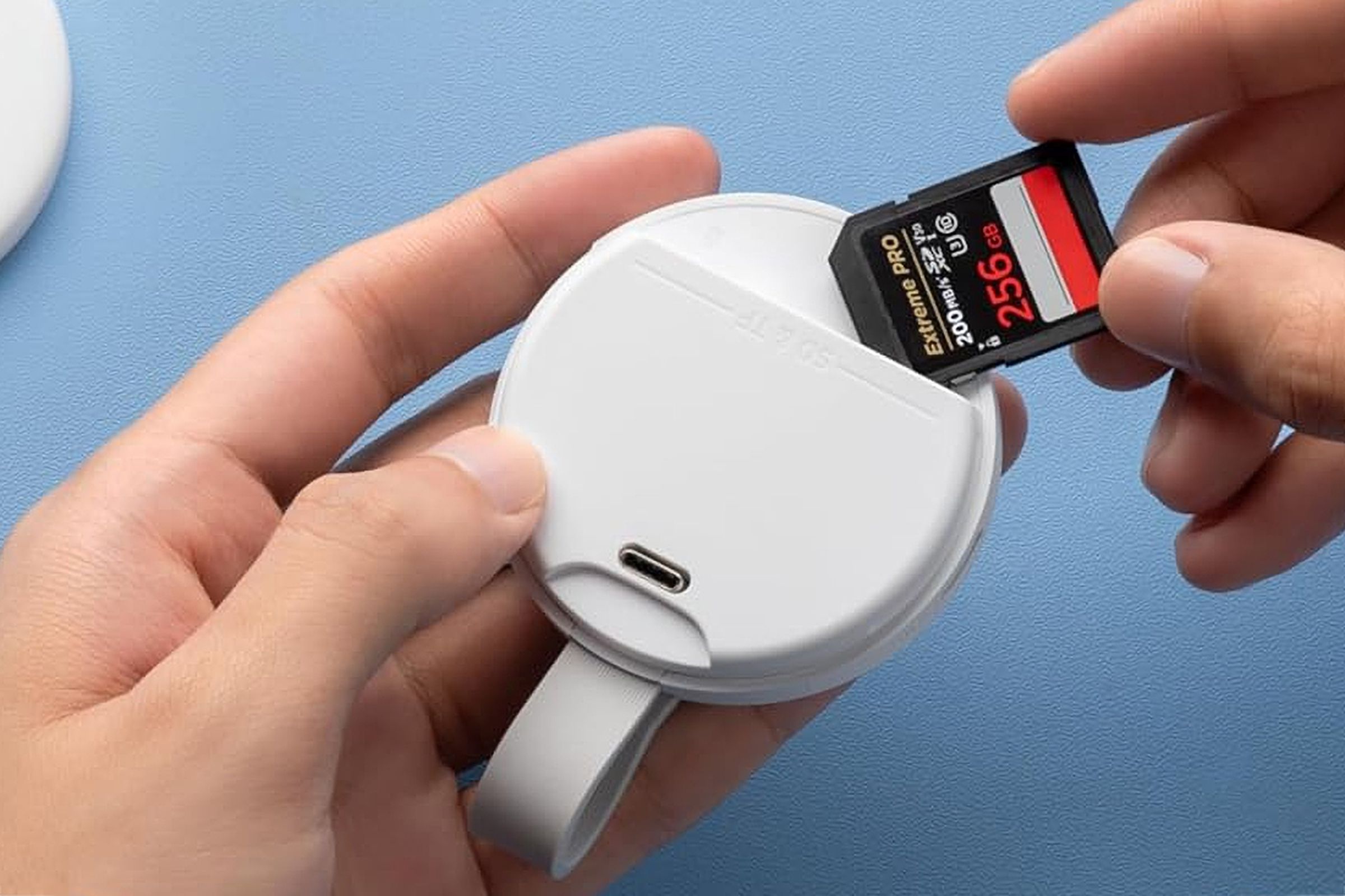 A user inserting an SD card into the white version of the Anker MagGo USB-C Adapter.