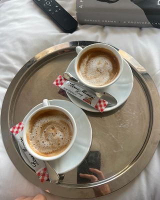 Two cups of coffee on a silver tray.