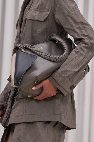 close up of Ferragamo model wearing dark grey bag