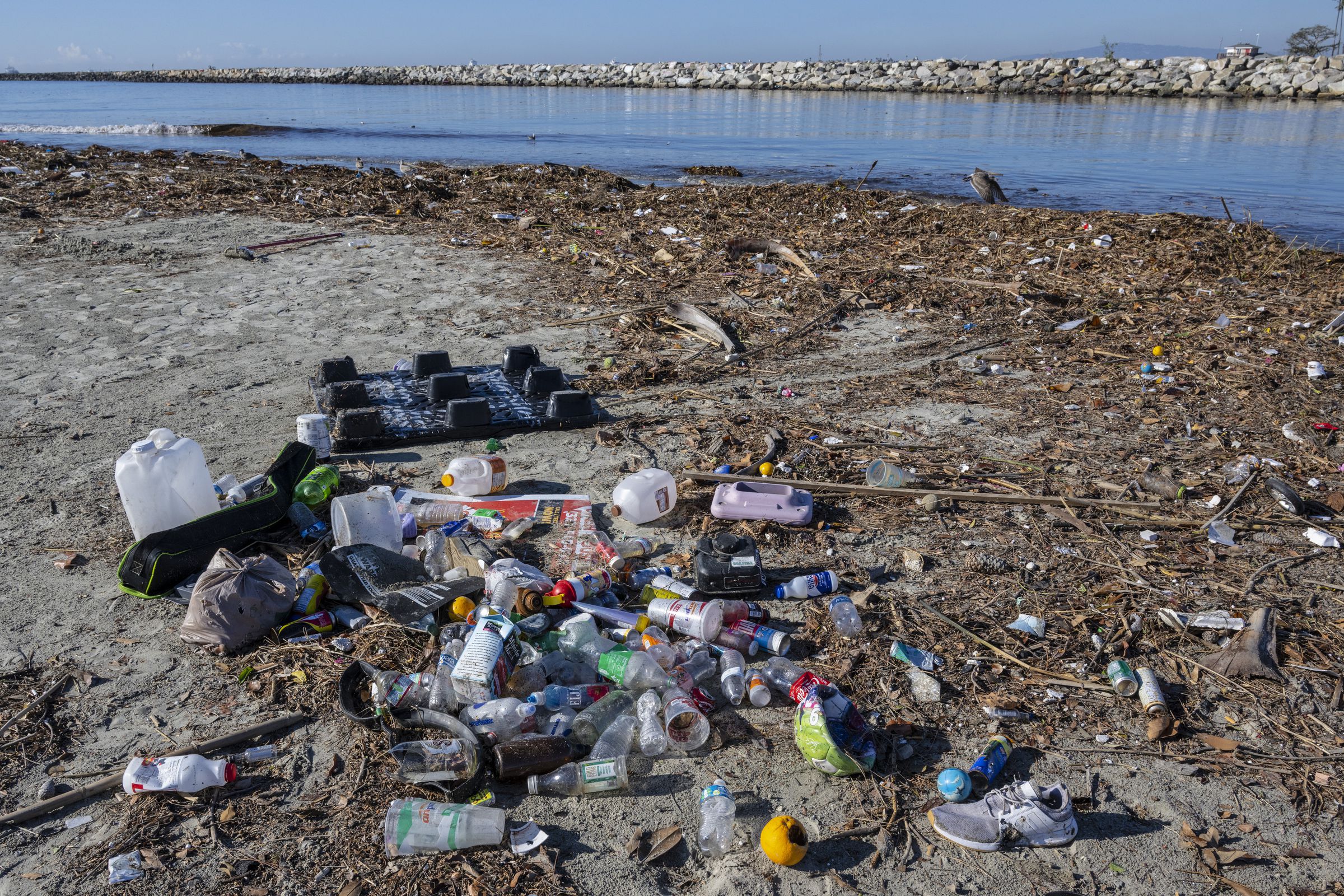 A pile of plastic bottles and other trash seen along a river bank.