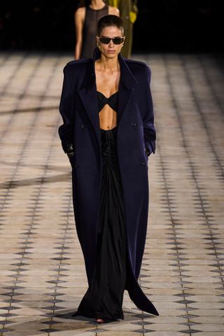 Saint Laurent model walks the spring/summer 2023 runway wearing a maxi coat