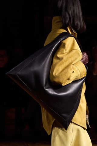 The smooth-leather Hop bag in black carried by a model during Bottega Veneta's fall/winter 2024 show.